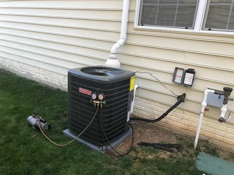 Goodman brand air conditioning unit with refrigerant lines and electrical connections newly installed outside home